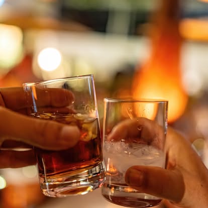 Two glasses clinking at Bellini — warm evening atmosphere