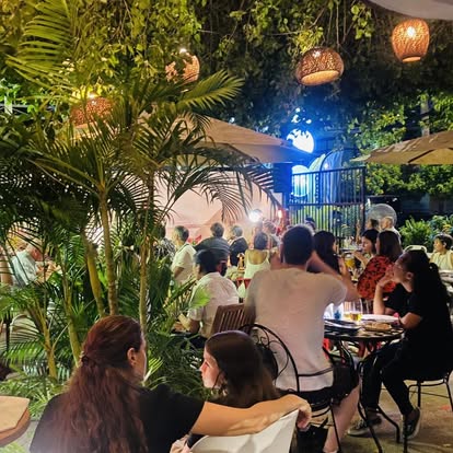 Bellini full garden at night — lush tropical plants and warm lanterns