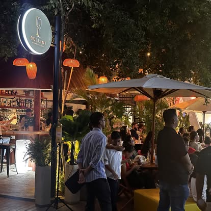Bellini entrance sign at night with full outdoor garden and guests