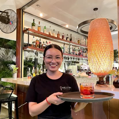 Bellini staff member serving a cocktail with a smile
